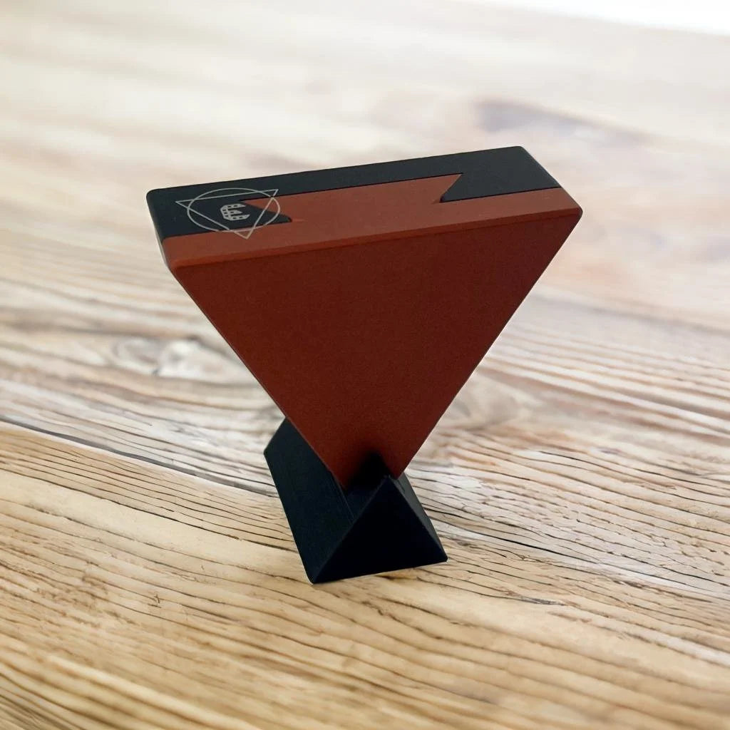 A wooden table with an UNLIMIT3D CRYPT3D Stand in black and royal red on it.